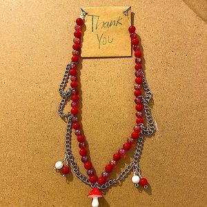 Necklace is red and white with a mushroom and two beads on both side.